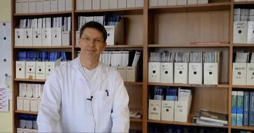 Diabetesfortbildung: Ein Arzt in weißem Kittel steht vor einem Büroschrank und erläutert einen komplexen Fall.