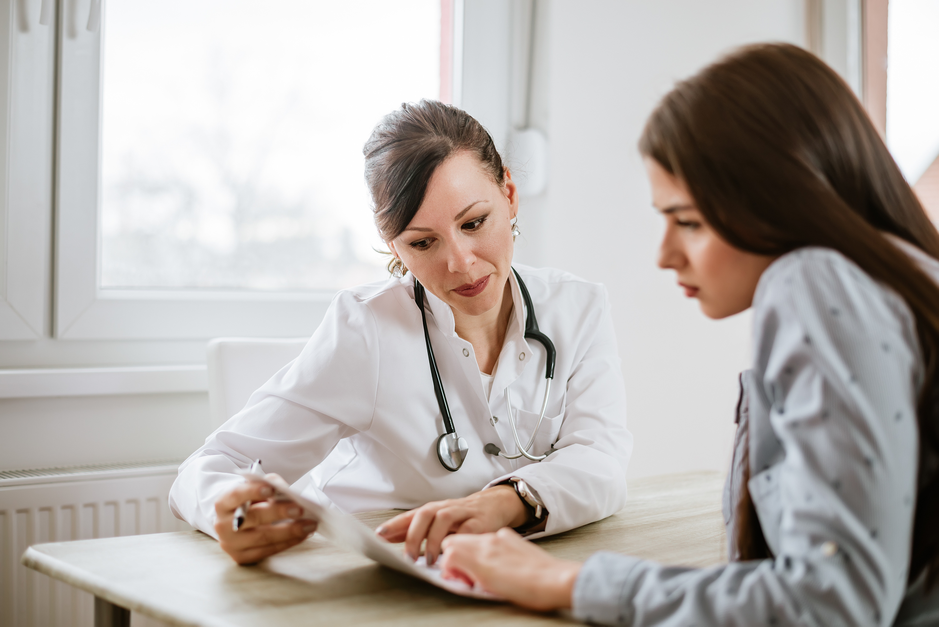 Bild: Mediziner und Patient lesen gemeinsam Materialien zum Thema Pflege.