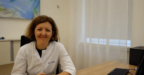 Diabetesfortbildung: Eine Ärztin in weißem Kittel sitzt lächelnd am Schreibtisch und erzählt von einem komplexen Fall.